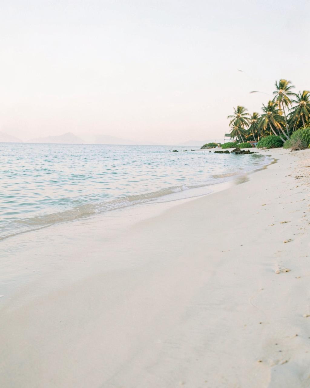 Quiet sandy beach with calm clear water at sunrise